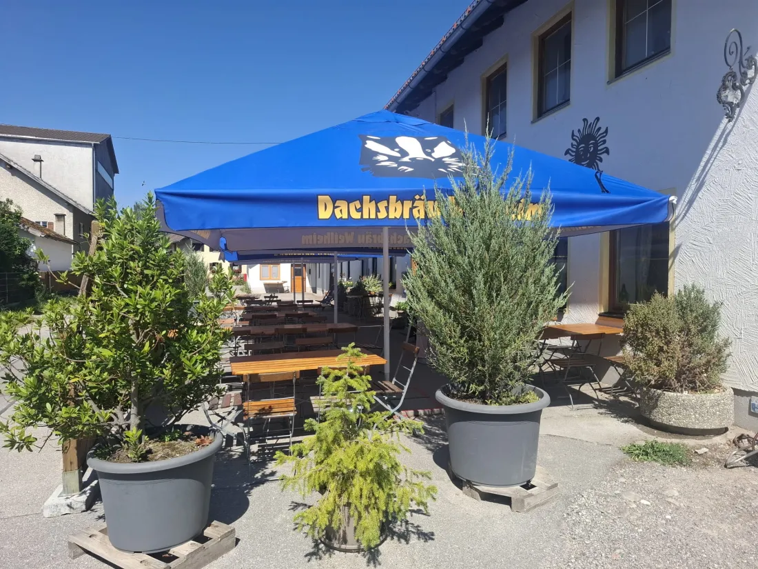 Sonniger Biergarten mit Dachsbräu-Schirm