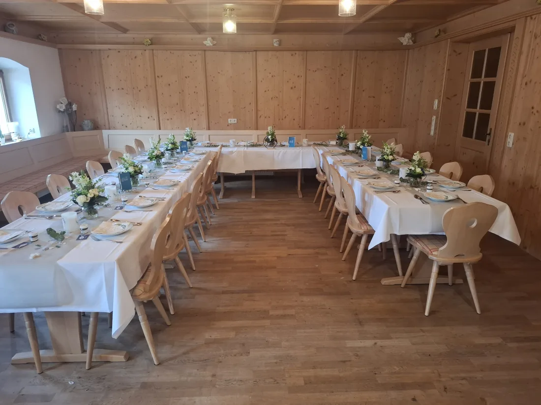 Festlich gedeckte Tafel im holzvertäfelten Stüberl mit Blumenschmuck